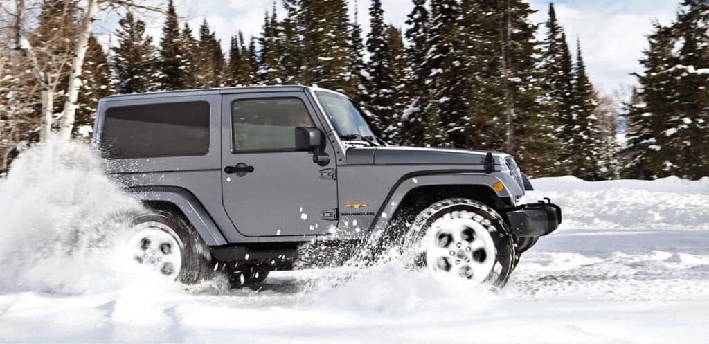 Dark Grey Jeep driving in snow.